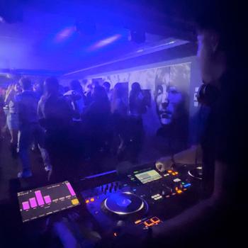 Energetic deejay standing in front of dancing people in club